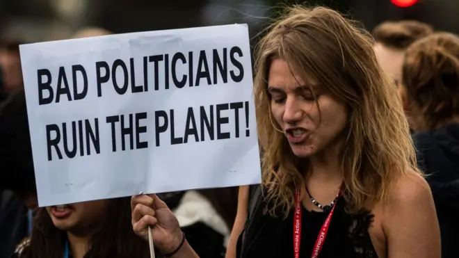 A la COP 25, une militante de la protection de l'environnement tient une pancarte accusant de "mauvais politiciens" de détruire la planète.