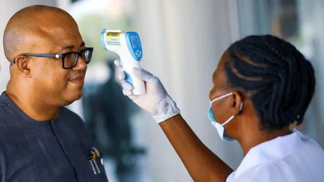 Dr. Chikwe Ihekweazu, di Director General of Nigeria Centre for Disease Control (NCDC) dey check im temperature during one diplomatic meeting for Ministry of Foreign Affairs in Abuja, Nigeria.