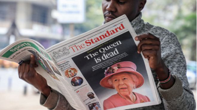 Un vendedor de periódicos leyendo un diario local que informa sobre la muerte de la reina Isabel II en la ciudad de Nairobi.
