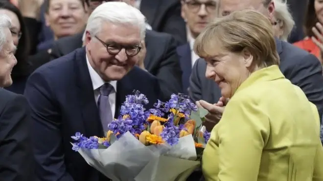 Frank-Walter Steinmeier receives flowers from Angela Merkel