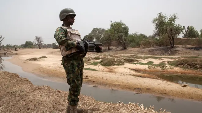 Soldier dey stand guard near di Yobe river wey separate Nigeria from Niger, for Damasak town for North East Nigeria on April, 25 2017