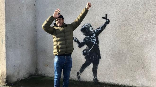 Британцы фотографируются на фоне нового граффити Бэнкси