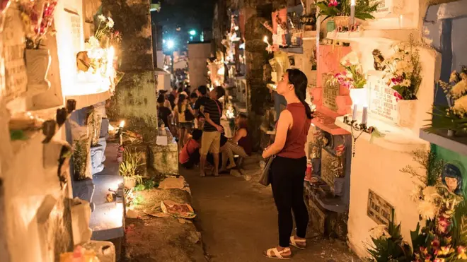 Seorang perempuan di tempat pemakaman umum di Manila, Filipina, pada peringatan Hari Orang Mati, November 2016.