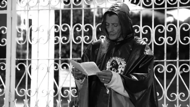 El animero reza frente a las puertas del cementerio antes de comenzar su recorrido por el pueblo.