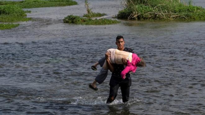 Venezolano cruzando el río Grande con una mujer en brazos.