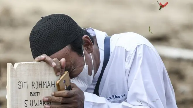 Warga menangis di atas nisan keluarganya di area pemakaman khusus COVID-19 di TPU Rorotan, Cilincing, Jakarta Utara, Senin (28/6/2021).