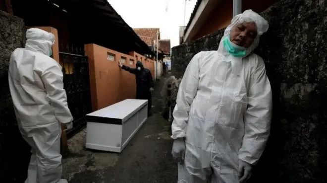 Tiga orang relawan tengah istirahat saat membawa peti jenazah seorang warga Kota Bogor yang meninggal akibat terpapar Covid, Kamis (08/07).