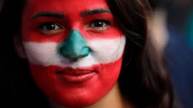 متظاهرة طلت وجهها بألوان علم لبنان