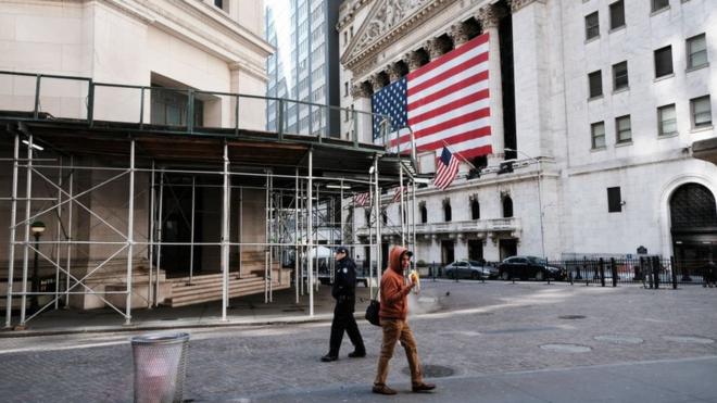 A man walks down an almost empty Wall Street