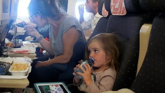 항공기 좌석에 앉아 기내식을 먹고 있는 엄마와 아이