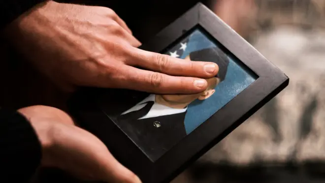 Max using his fingers to conceal his face on a photograph of himself as an airman