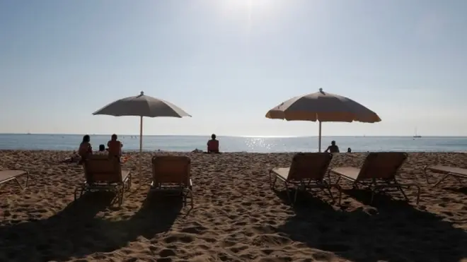 People sunbathe on a hot day in Barceloneta beach in Barcelona, Spain, 15 October 2017