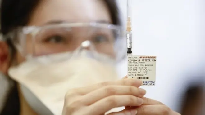 คนกำลังถือเข็มวัคซีนไฟเซอร์