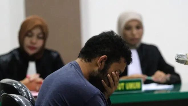 Salah seorang dari dua pria bereaksi ketika hakim membacakan vonis.