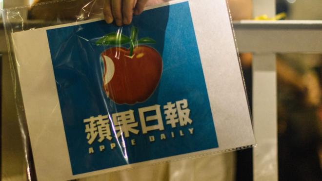 香港將軍澳壹傳媒總部大樓外一名支持者舉起《蘋果日報》標誌聲援員工（24/6/2021）