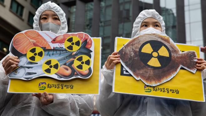 韩国环保活动人士在首尔日本大使馆外举起象征海鲜受核辐射污染的抗议标语牌（13/4/2021）