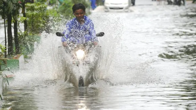 一個騎摩托車的人的經過雅加達一條被水淹沒的街上。雅加達正面臨海平面上升和地面沉降帶來的雙重挑戰（圖片來源：Alamy）