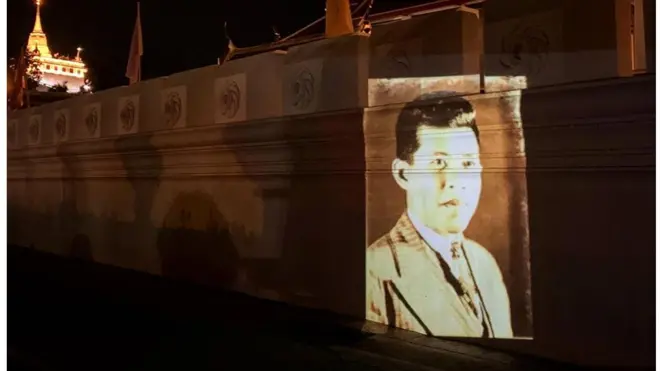 ภาพฉายโปรเจกเตอร์รูปนายปรีดี พนมยงค์ ที่ศิลปินกลุ่ม Headache Stencil แสดงบนกำแพงวัดราชนัดดาในเช้ามืดของวันที่ 24 มิ.ย. 2563 ก่อนที่หนึ่งในศิลปินจะถูกบุคคลที่เขาเชื่อว่าเป็นเจ้าหน้าที่นอกเครื่องแบบติดตามที่บ้านพัก