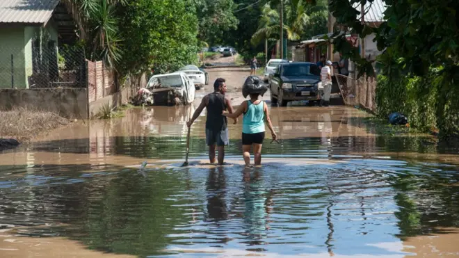 Couple wade through flooded street in La Lima, Honduras, on 8 November 2020