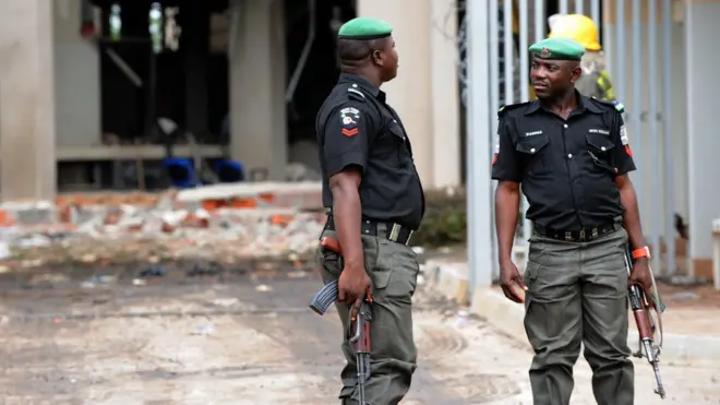 Nigeria Policemen dey stand in front of building