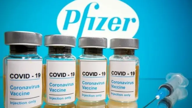 Vials and medical syringe are seen in front of Pfizer logo in this illustration