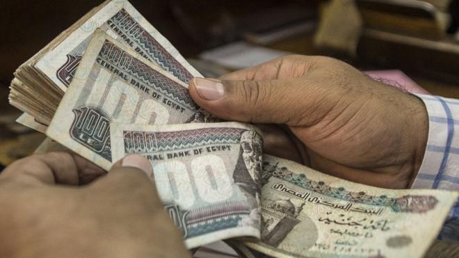 رجل يعد أوراق مالية فئة مئة جنيه مصري