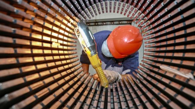 在中国东部江苏省南通市的一家工厂里，一名工人正在检查风力涡轮机使用的转子铁芯。