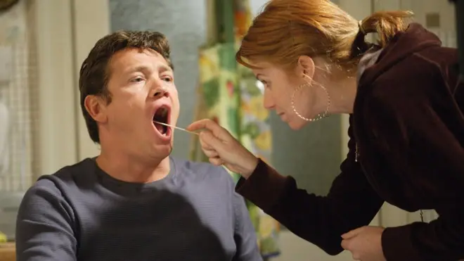 Una mujer toma una muestra de mucosa de la boca de un hombre