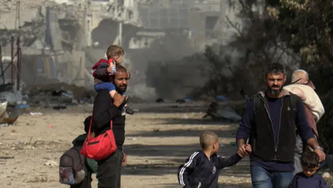 A grab from an AFPTV video shows Palestinians fleeing Gaza City on foot as an Israeli armoured vehicle drives past them amid ongoing battles between Israel and the Palestinian Hamas movement on November 18, 2023. (Photo by Belal Al SABBAGH / AFP) (Photo by BELAL AL SABBAGH/AFP via Getty Images)