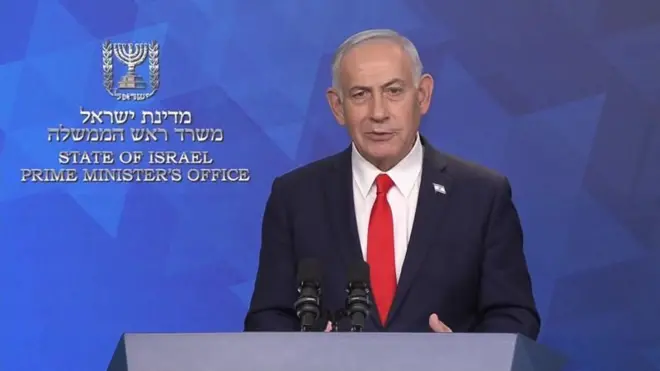 Netanyahu kürsüde, Başbakanlık Ofisi yazılı mavi fonun önünde konuşuyor. 