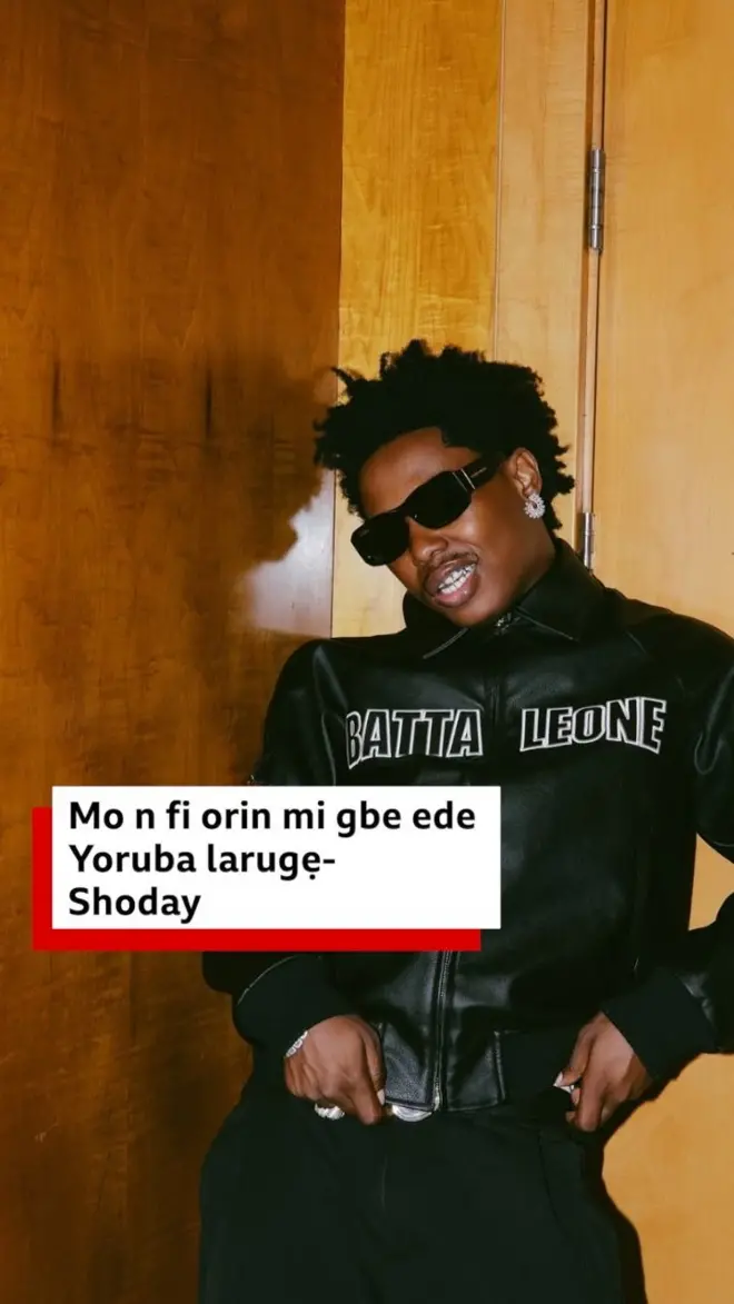 Shodey wọ asọ toke tilẹ dudu, o lo awo oju, o si ta irun rẹ ni koko
