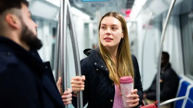 A woman talking to a man on an underground train