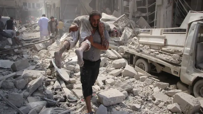 A man carries an injured man in Idlib, Syria, 10 September