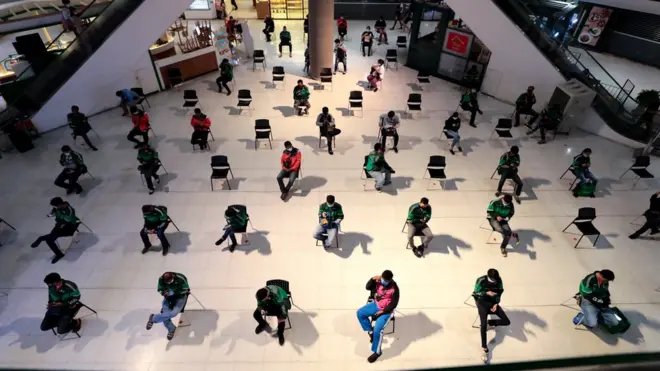 พนักงานรับส่งอาหารจากหลายบริษัทเข้าคิวรับสินค้าเพื่อไปส่งสินค้าให้ลูกค้าที่ทำงานจากที่บ้านในช่วงการแพร่ระบาดของเชื้อโควิด-19