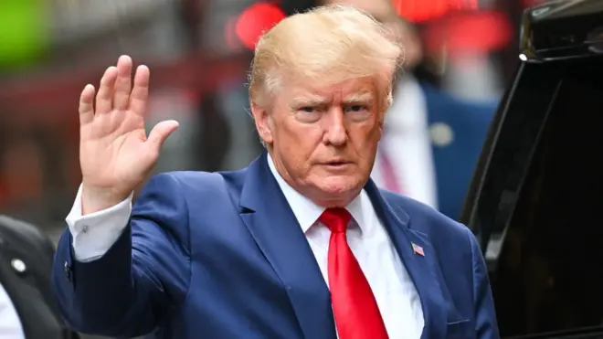 Donald Trump waves while exiting a vehicle