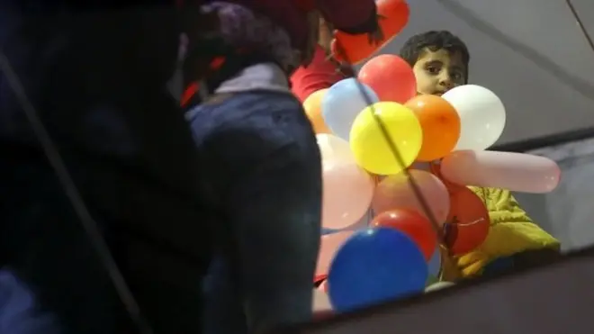 Boy holding bunch of balloons