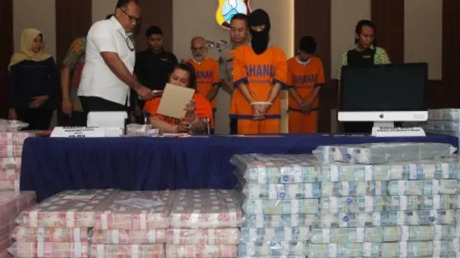 Polisi menghadirkan tersangka dan barang bukti uang saat ungkap kasus investasi ilegal di Polda Jawa Timur, Surabaya, Jawa Timur, Jumat (10/1/2020). Polda Jawa Timur menetapkan empat tersangka atas kasus dugaan investasi ilegal 'MeMiles' yang dikelola PT Kam And Kam dan menyita sejumlah barang bukti salah satu diantaranya uang sekitar Rp122,3 miliar.