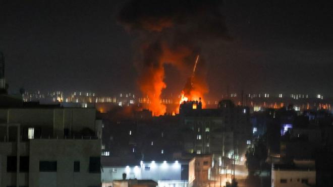 Explosions light-up the night sky above buildings in Gaza City as Israeli forces shell the Palestinian enclave,
