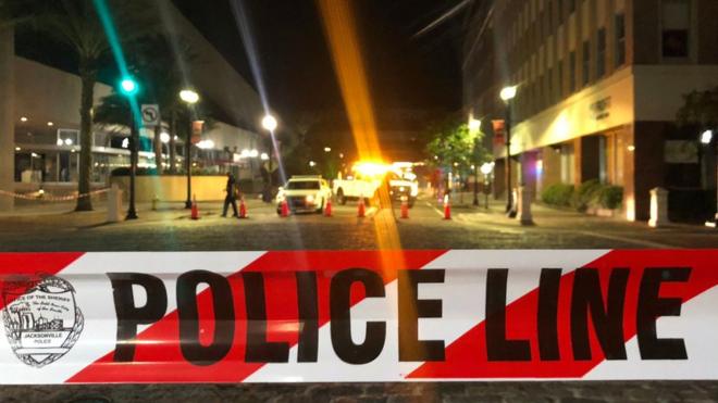 This photo shows a police car behind police tape blocking a street leading to the Jacksonville Landing area in downtown Jacksonville, Florida, August 26, 2018, where two people were killed and 11 others wounded.
