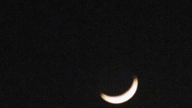 A crescent moon (below) and the planets Venus (left) and Jupiter (right) are seen in a rare alignment over Hong Kong on December 1, 2008