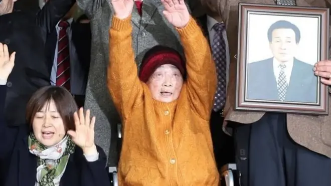 Kim Seong-ju (tengah) di antara para korban dan keluarga yang merayakan kemenangan mereka di Seoul.