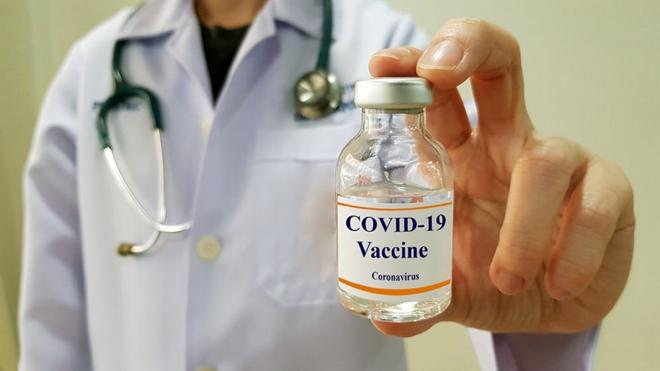 Médico segurança frasco onde está escrito "Covid-19 Vacina"