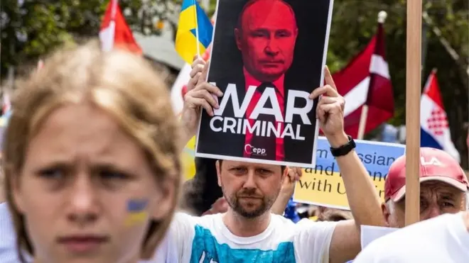 A demonstrator holds up a placard depicting Russian President Putin with the words "War Criminal" during a rally against the war in Ukraine, in Melbourne, Victoria, Australia, 27 February 2022