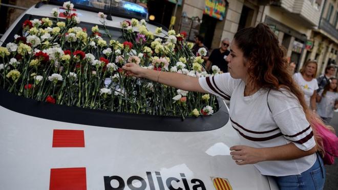 Демонстрантка украшает цветами машину каталонской полиции во время демонстрации в поддержку референдума о независимости, Барселона, 24 сентября 2017 г.