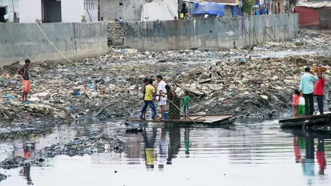 Жителям трущоб Мумбаи приходится пересекать канаву на плоту.