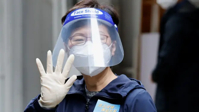 Hong Kong Chief Executive Carrie Lam, wearing a face mask and a shield, waves to the media after delivering anti-epidemic service bags to residents during the coronavirus disease (COVID-19) pandemic, in Hong Kong, China, April 2, 2022.