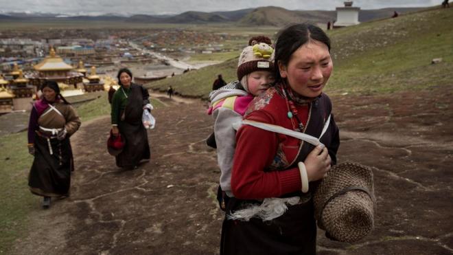 Mulher tibetana carregando bebê nas costas