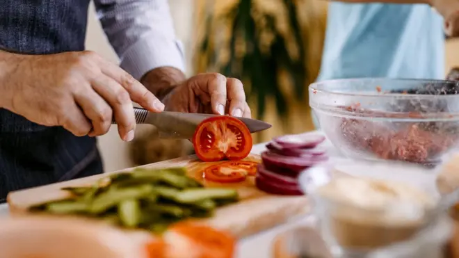 Stock shot of a man's hands cutting a tomato
