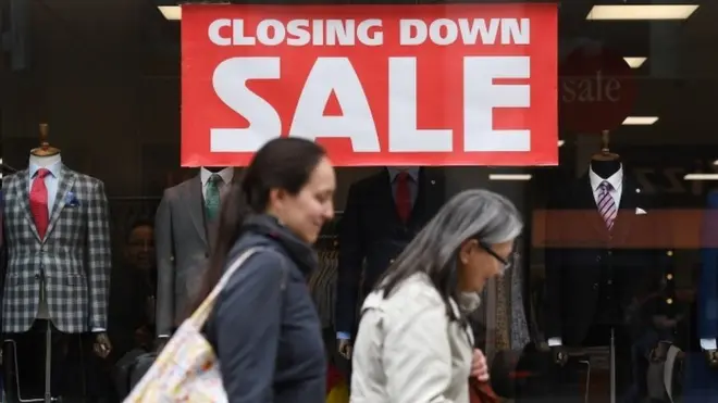 폐점 안내 간판 앞을 지나는 행인들