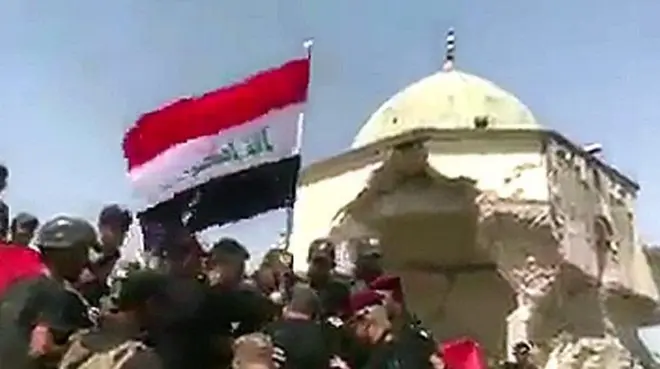 قوات جهاز مكافحة الإرهاب ترفع العلم العراقي فوق ركام جامع النوري في المدينة القديمة في الموصل .